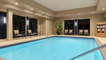 Een binnenzwembad, ligstoelen bij het zwembad