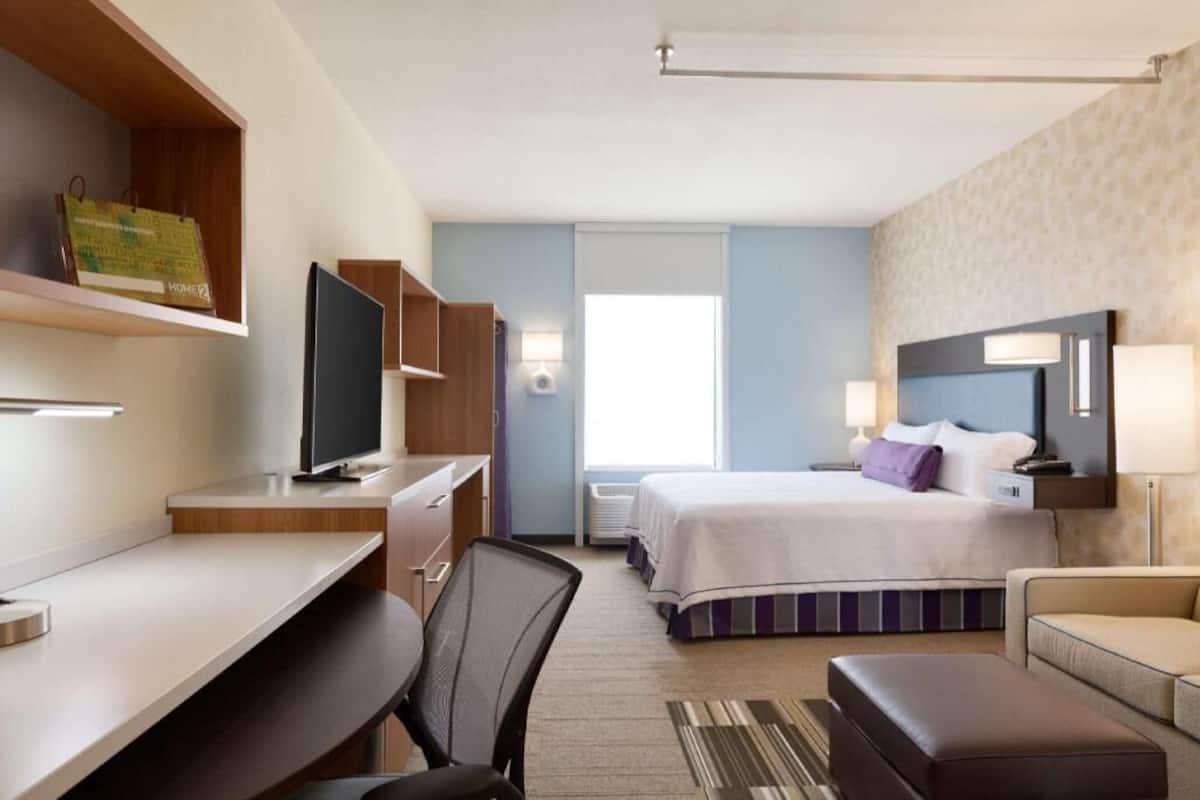 A hotel room with a bed, desk, chair, and television.