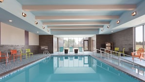 Une piscine avec des chaises et une vue sur l’extérieur.