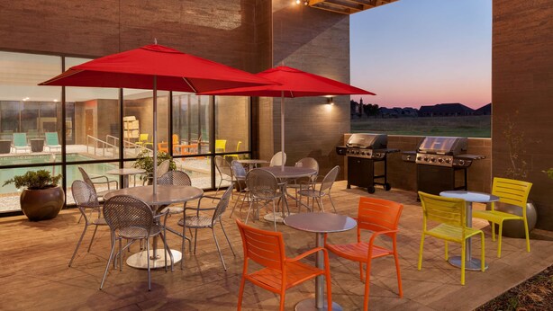 Une terrasse extérieure avec des tables et des chaises, un barbecue et des guirlandes lumineuses.