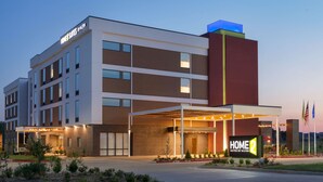 Un hôtel moderne doté d’une entrée couverte, de plusieurs étages et d’une enseigne indiquant qu’il s’agit d’un Home 2 Suites by Hilton.