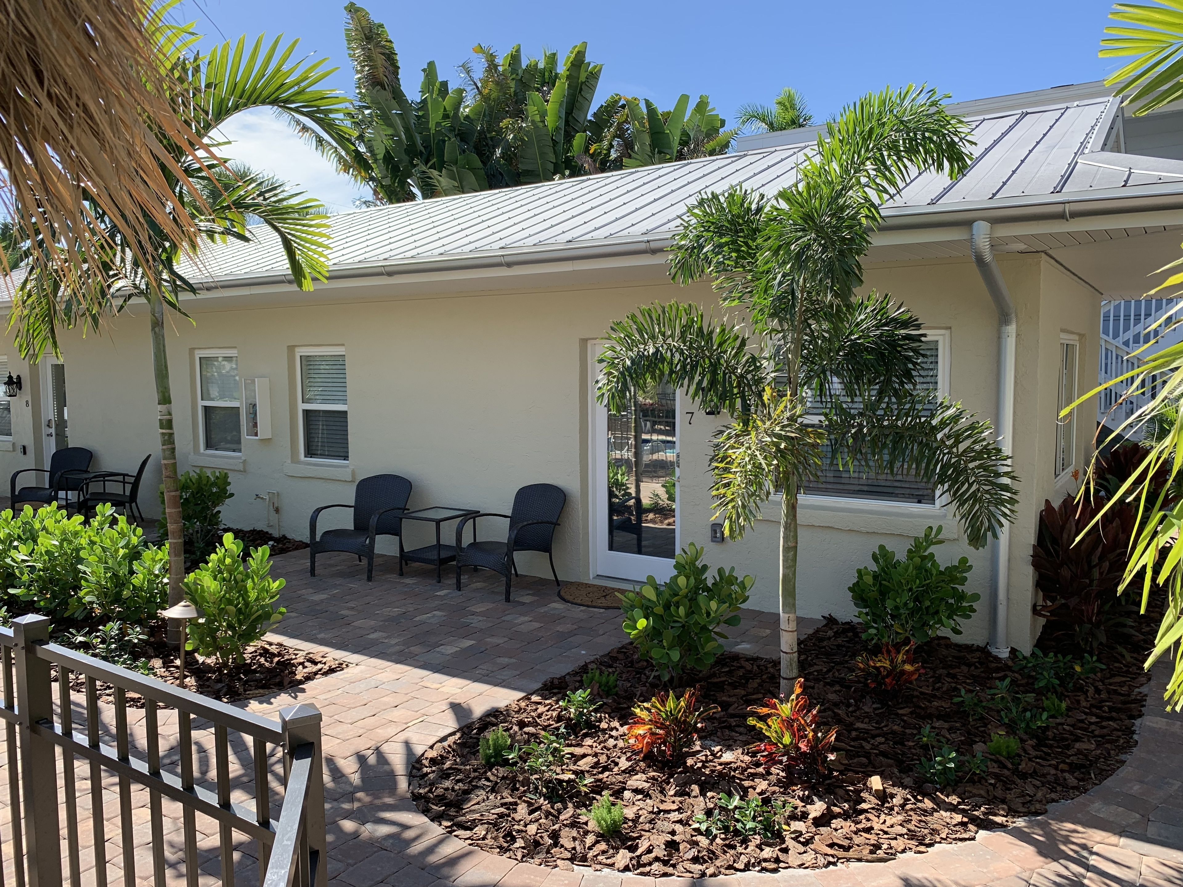 A building with a patio area, outdoor seating, and a variety of plants.