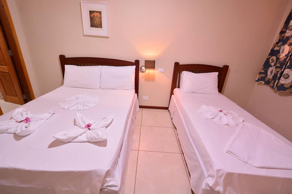 Two twin beds with white linens and towels arranged in a floral pattern.