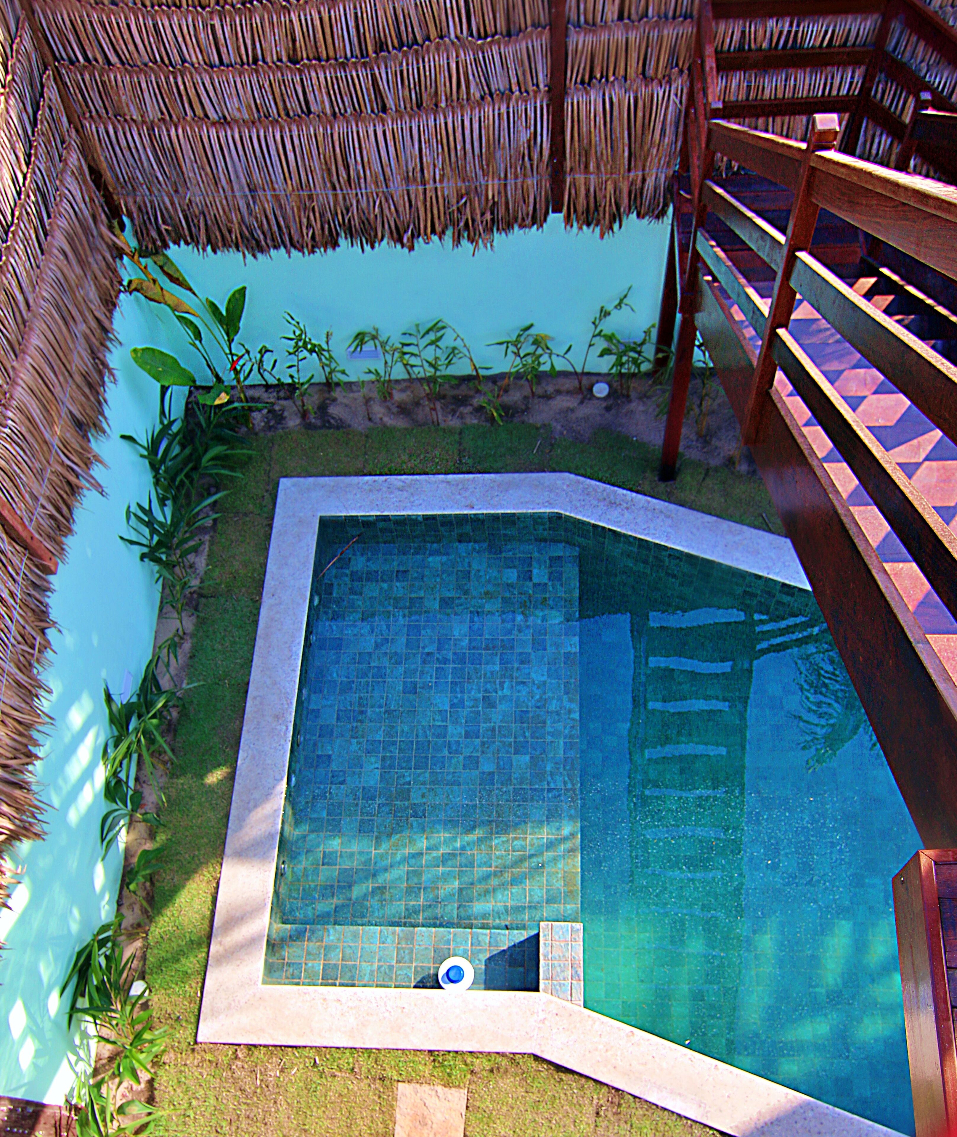 A swimming pool with a tiled edge, surrounded by a grassy area and a wooden deck.