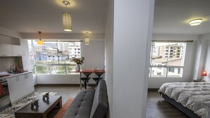 A modern apartment with a kitchen, dining area, and a large bed. - Terra Nostra Suites (Cusco)