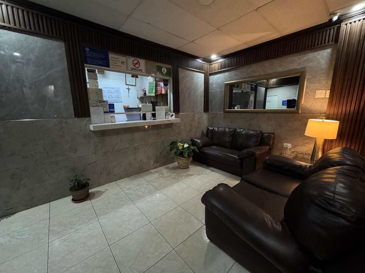 A reception area with a counter, seating, and a mirror.