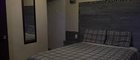 Ein Schlafzimmer mit einem Bett, einem Deckenventilator, einem Spiegel und einer Wandleuchte.