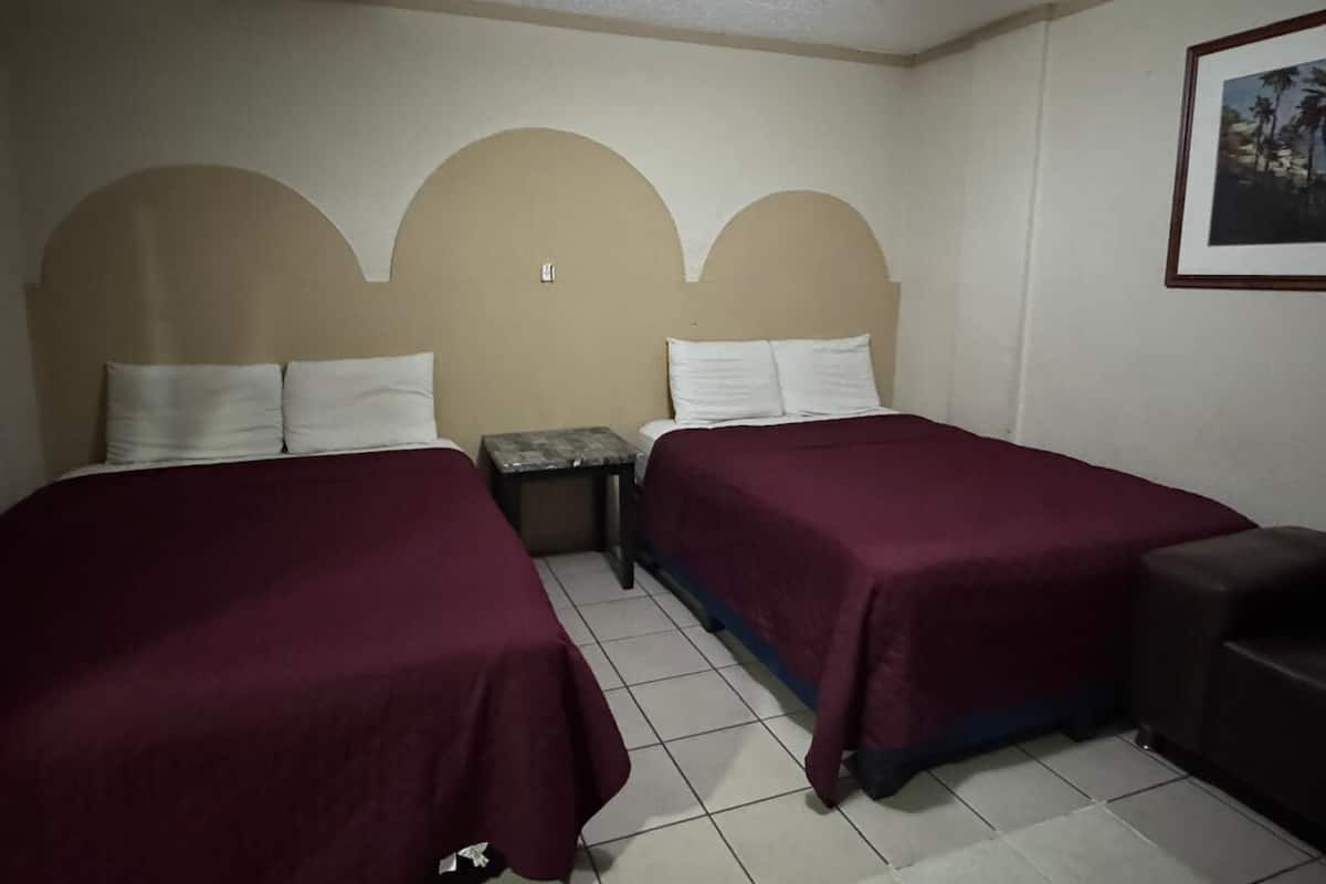 Une chambre d’hôtel avec deux lits simples, une petite table et un canapé.
