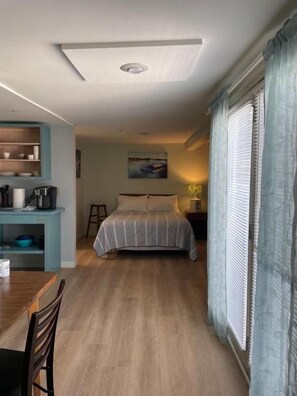 A bedroom with a bed, a desk, and a chair. There is a window with curtains and a painting on the wall. - The Lynwood Inn (York Beach)