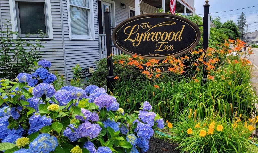 Señal de The Lynwood Inn con un jardín delantero con hortensias y otras plantas.