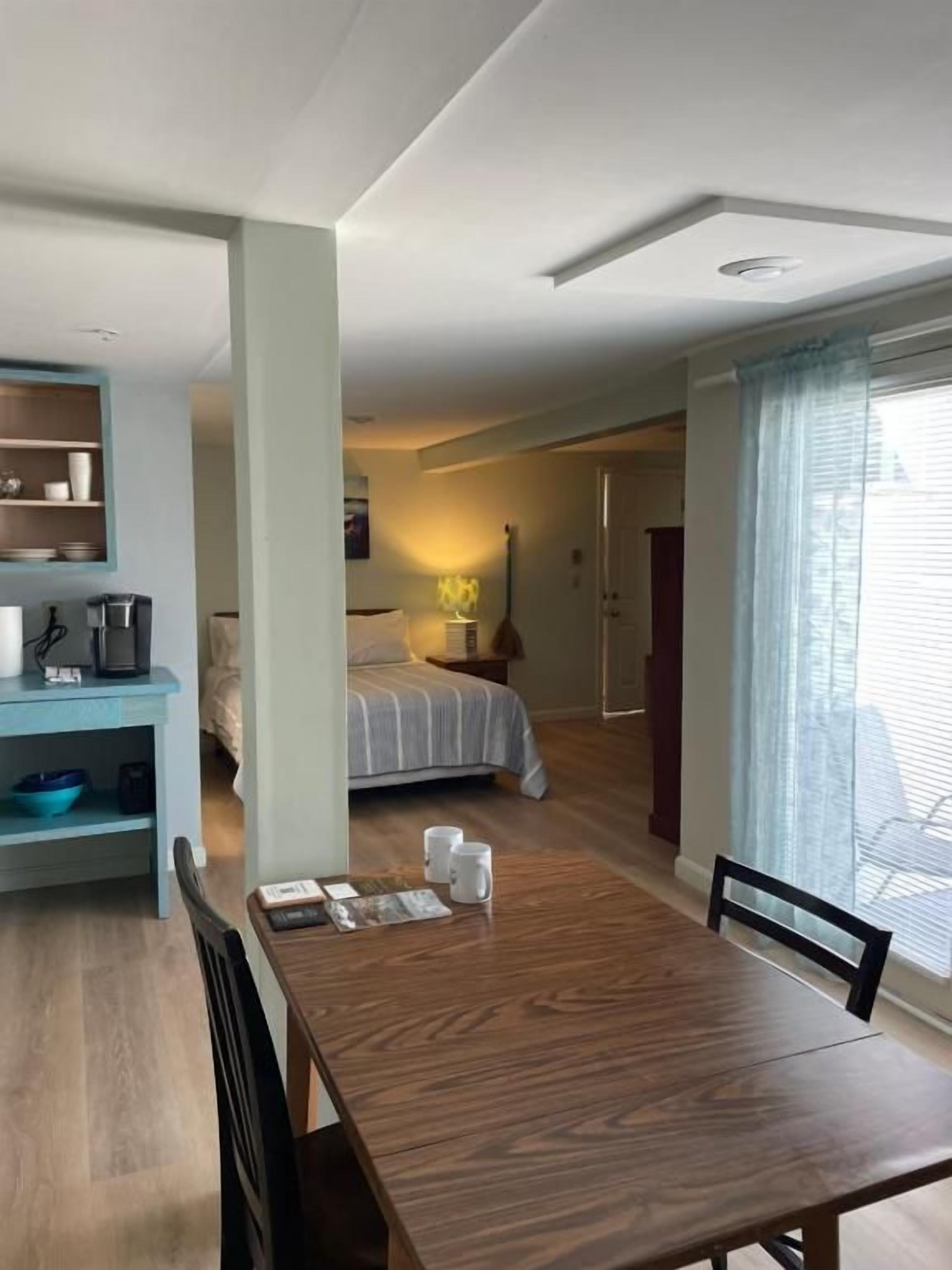A compact living space with a dining area, kitchenette, and a bedroom.