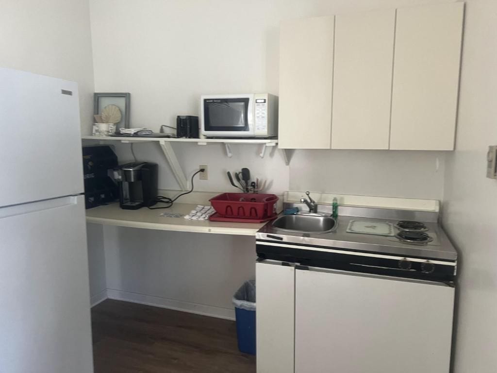Cocina compacta equipada con refrigerador, microondas, cafetera, pileta y lavavajillas pequeño.