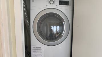 A compact, white stacked washer and dryer unit with a control panel and a digital display.