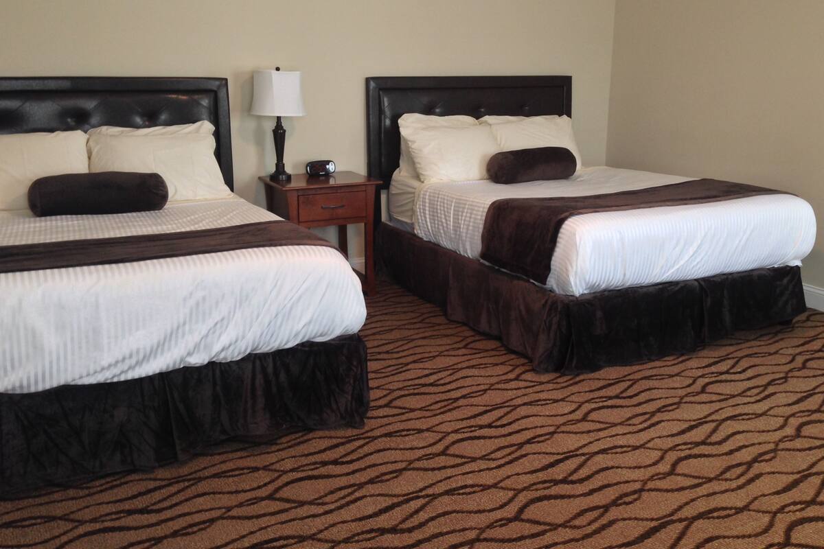 Two single beds with dark headboards, white bedding, and a brown patterned carpet.