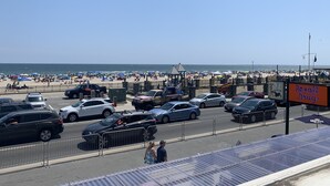 A beachside parking area with cars and a pedestrian walkway. - The Pelham Resort Motel (Hampton)