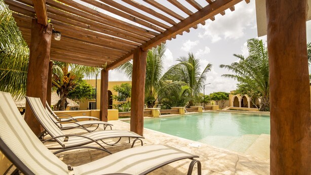 Un espace aménagé au bord de la piscine, avec des chaises longues et une pergola en bois.