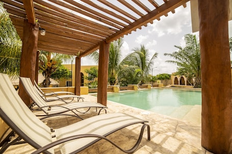 Una piscina al aire libre, sillones reclinables de piscina