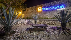 Un mur de pierre sur lequel est apposée une enseigne au néon pour le Tecnohotel Valladolid.