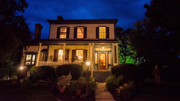 A two-story house with a porch, a front door, and a small garden area with potted plants. - Borland House Inn (Montgomery)