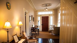 A hallway with a wooden floor, a dining table with chairs, a lamp, and a framed picture on a side table. - Borland House Inn (Montgomery)