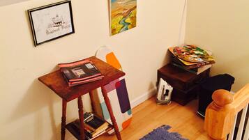 A room with a wooden table, a framed picture, a colorful painting, and a small stool.