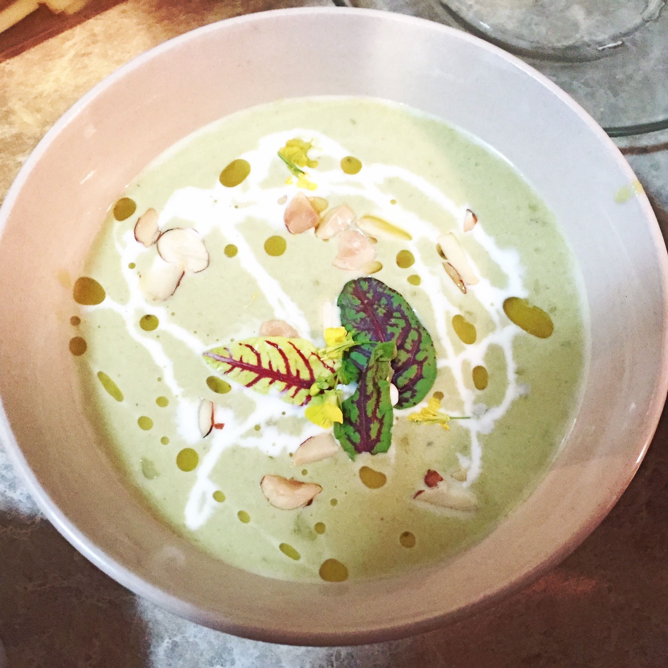 Un tazón de sopa con textura cremosa, adornado con nueces y verduras de hoja.