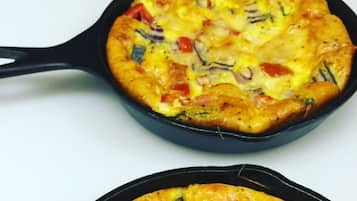Three cast iron skillets filled with a baked dish, likely a frittata, on a white surface.