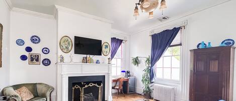 A traditional living room with a fireplace, a television, and a blue sofa.