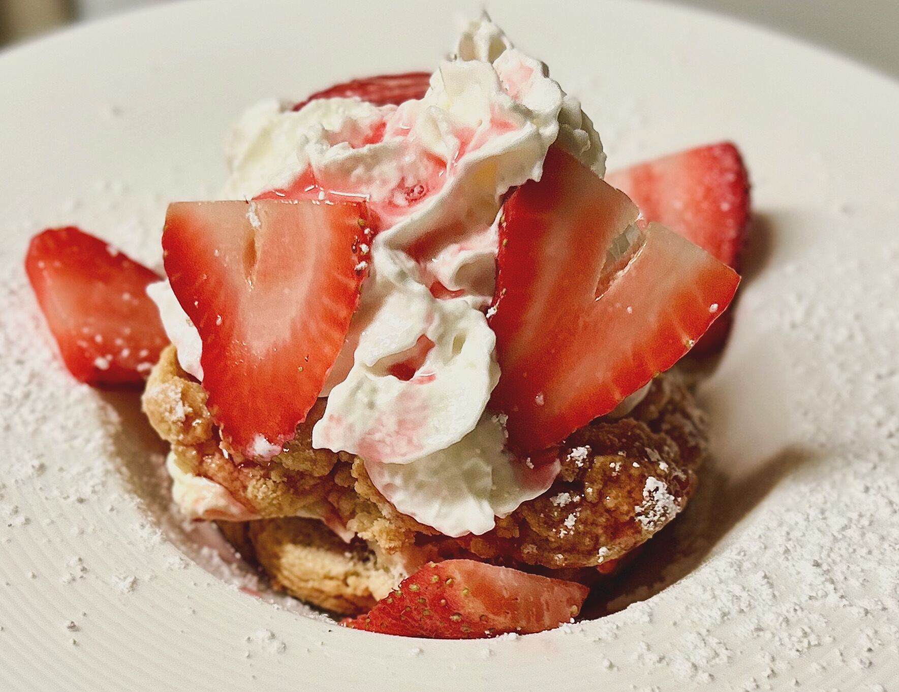 Postre con crema batida y fresas en un plato.