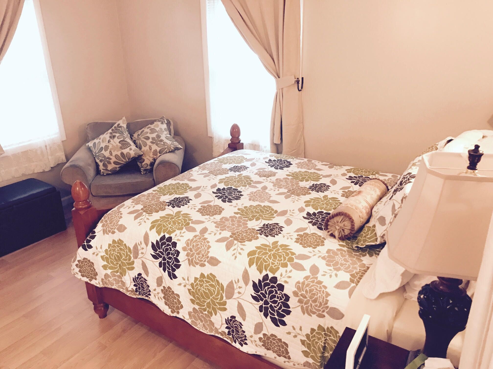 A bedroom with a bed, a chair, a nightstand, and a lamp.