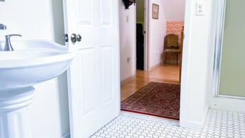 A bathroom with a white sink and a door leading to a hallway with a patterned floor.