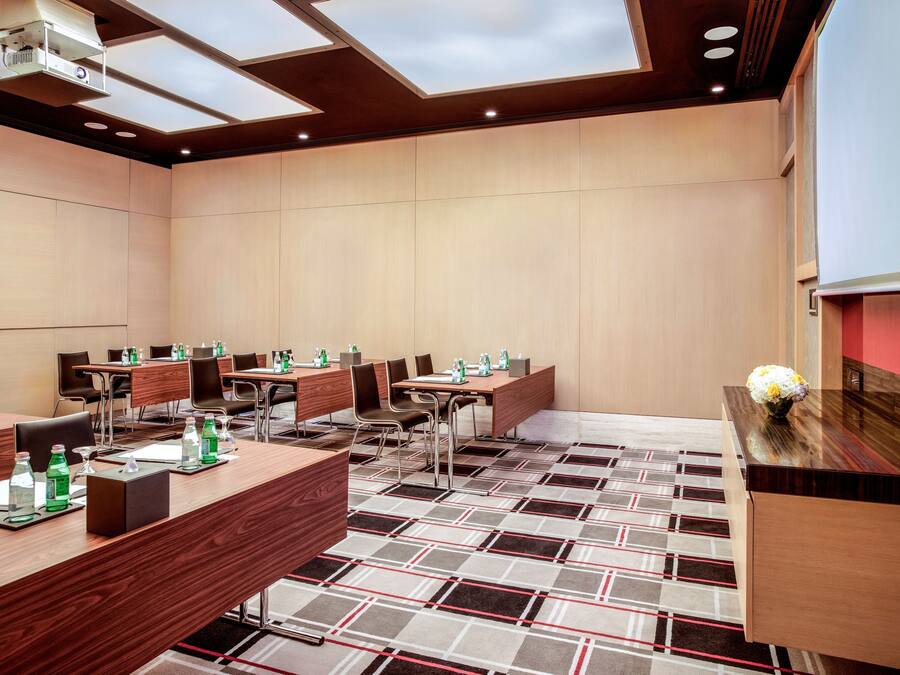 A conference room with multiple tables, chairs, and a projector screen.