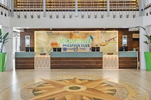 A reception desk with a map and parrot decoration, surrounded by a spacious lobby with a star-patterned floor.