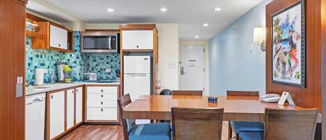 A compact kitchen with a microwave, refrigerator, and wooden cabinets.