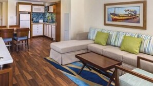 A modern living room with a sofa, a coffee table, and a dining area with a table and chairs.