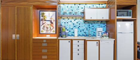 A compact kitchen with wooden cabinets, a tiled backsplash, and a microwave.