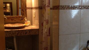 A bathroom with a sink, mirror, and shower curtain.