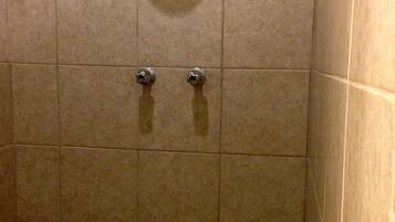 A tiled shower stall with a hand dryer and a towel rack.