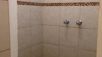 A shower area with tiled walls and floor, a metal shower head, and a towel rack.