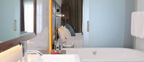 A modern bathroom with a large bathtub, a sink, and a mirror.