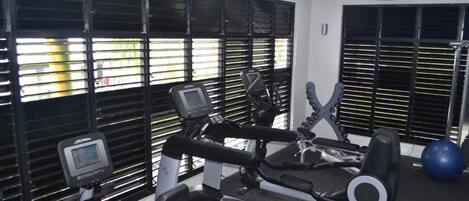 A gym with exercise equipment, including treadmills and a stationary bike, and a blue exercise ball.