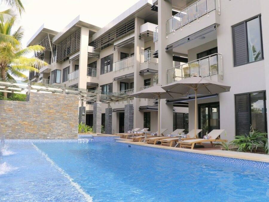 A modern hotel with a swimming pool, lounge chairs, and a stone wall.