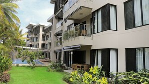 A multi-story hotel with balconies, a swimming pool, and lush greenery. - The Palms Denarau Fiji (Nadi)