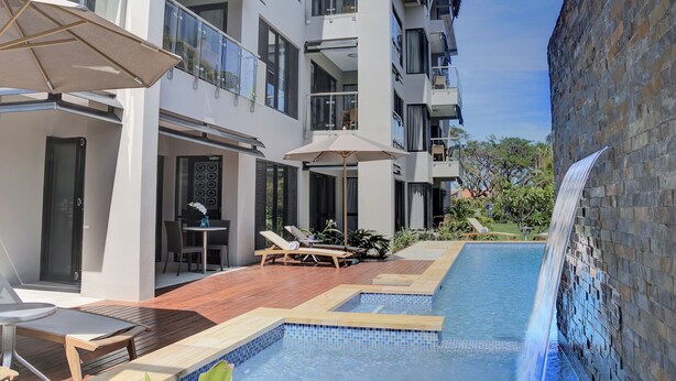 A modern hotel with a swimming pool, outdoor seating, and a waterfall feature. - The Palms Denarau Fiji (Nadi)