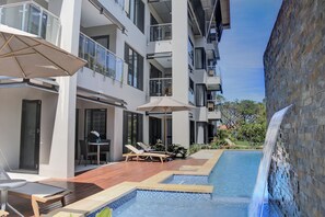 A modern hotel with a swimming pool, outdoor seating, and a waterfall feature. - The Palms Denarau Fiji (Nadi)