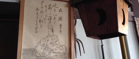 A traditional Japanese room with tatami flooring, a shoji screen, and a wooden calligraphy scroll.