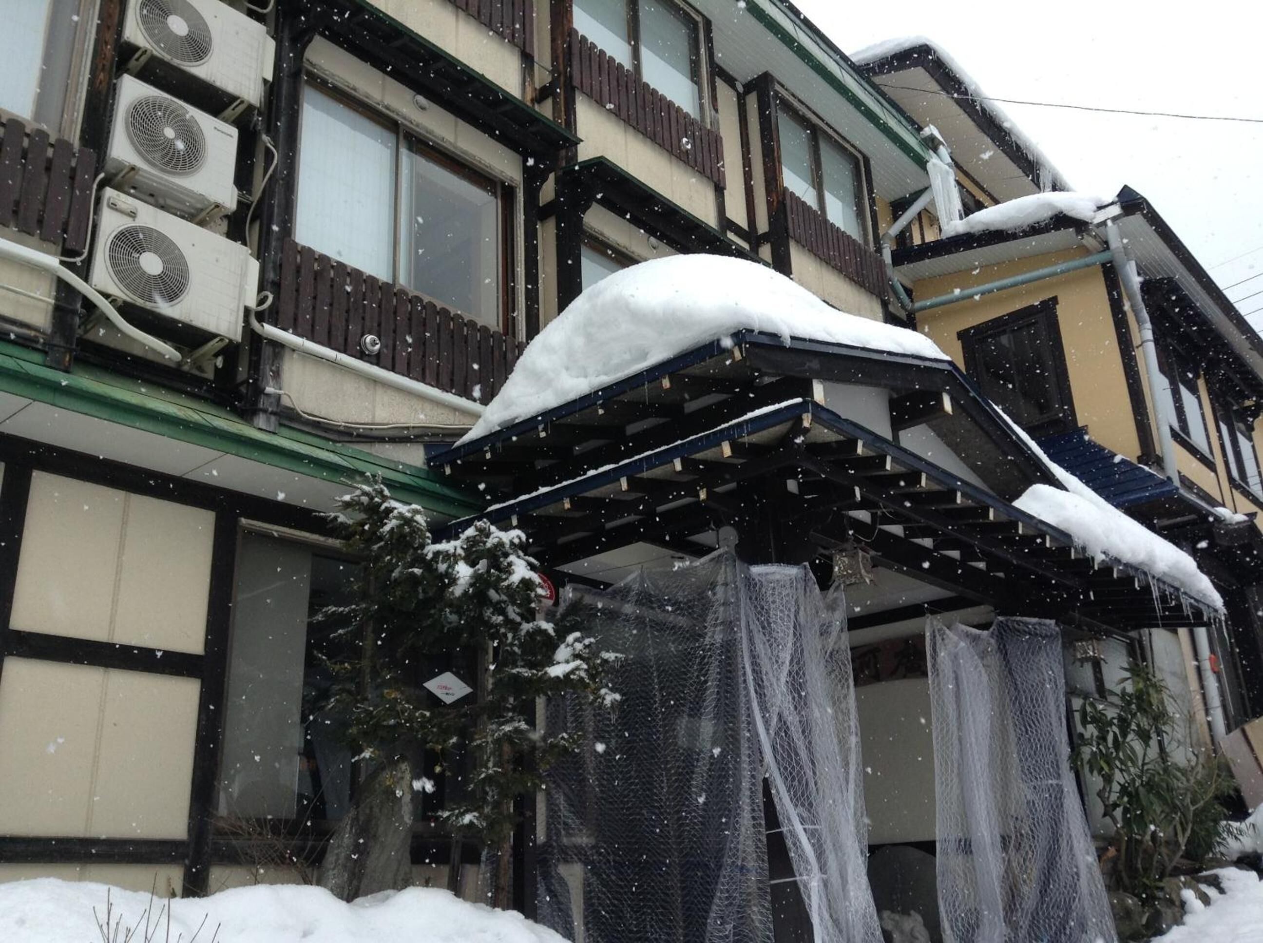 A building with multiple air conditioning units, a covered outdoor area, and snow accumulation.