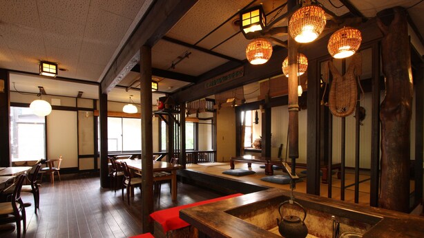 Interior de un restaurante japonés tradicional con suelos de madera, esteras de tatami, mesas bajas y faroles de papel colgantes.
