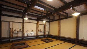 Una habitación tradicional japonesa con esteras de tatami, vigas de madera y una pequeña plataforma de madera.