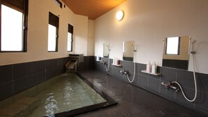 Un baño moderno con una bañera de hidromasaje con mampara de vidrio, varios lavamanos y un espejo grande.
